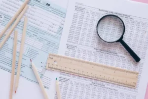 A high angle view showing IRS tax forms with pencils, ruler, and magnifying glass for financial planning.